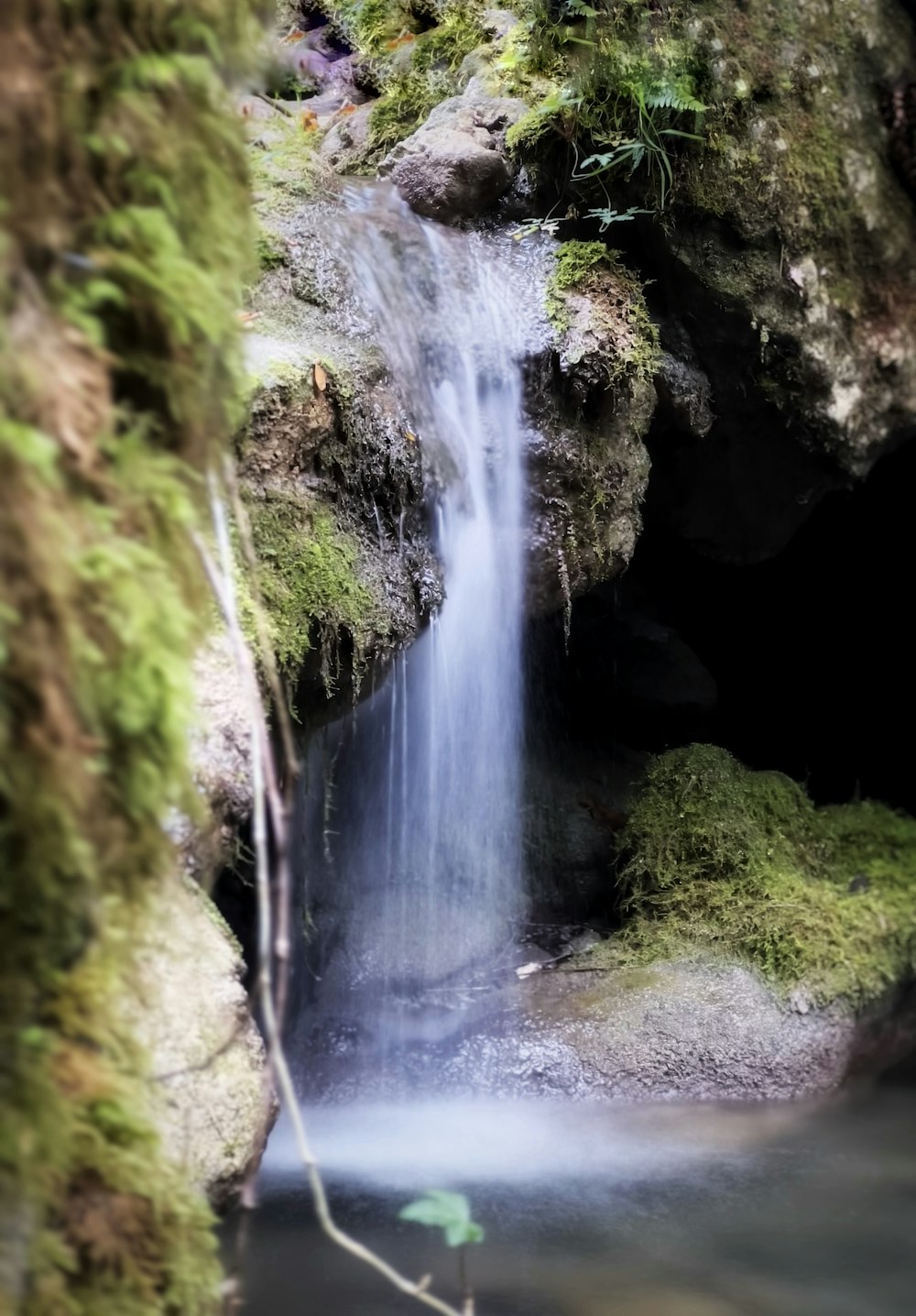 a small waterfall is coming out of a cave