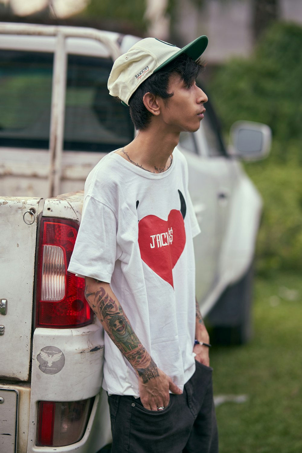 a man with a heart on his shirt standing next to a truck