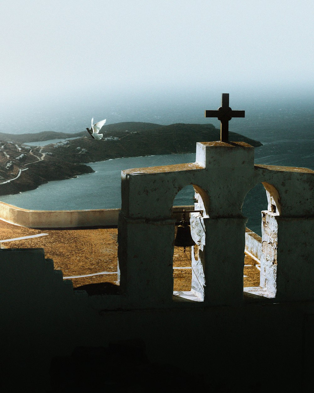 une croix au sommet d’un bâtiment surplombant un plan d’eau