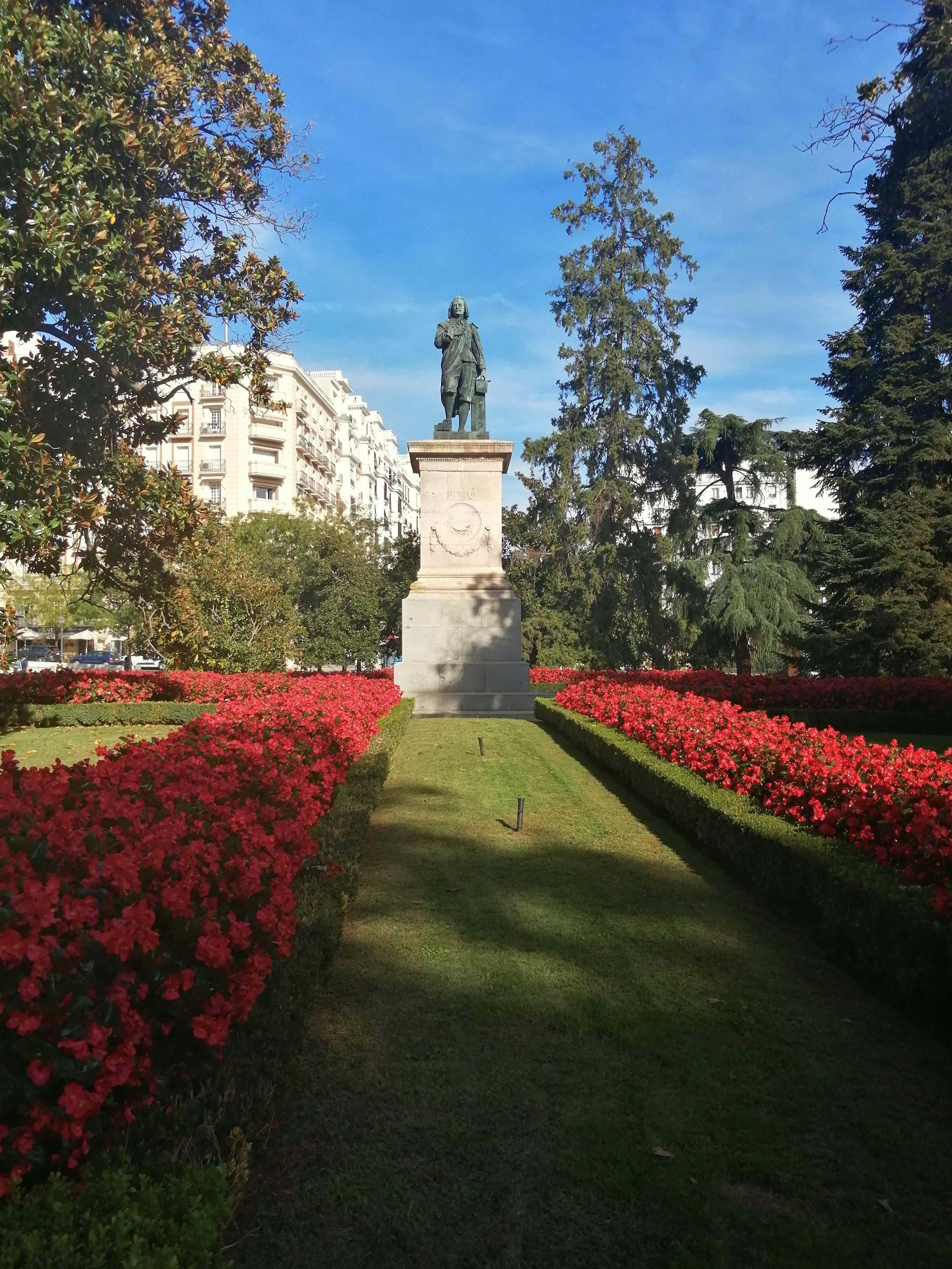a statue in the middle of a flower garden