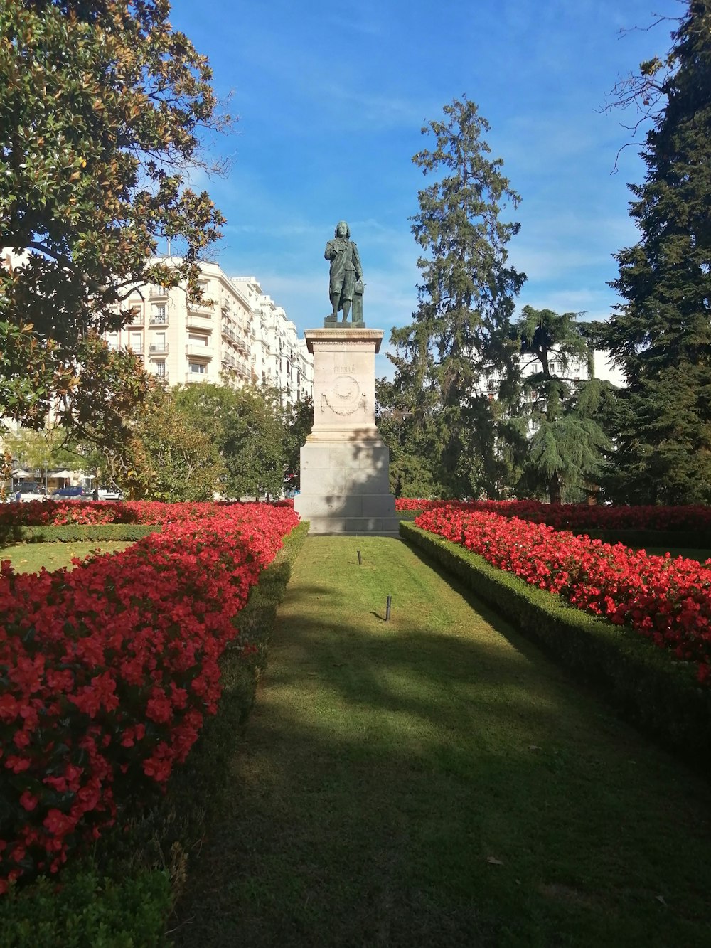 a statue in the middle of a flower garden