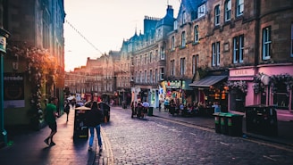 A bustling historic street in Savannah, Georgia, with cobblestone roads and vintage lampposts under a golden sunset.
