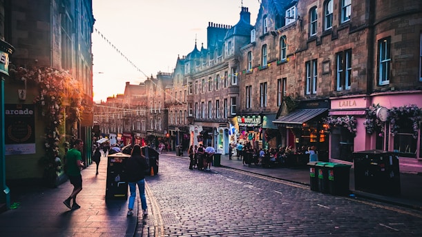 A bustling historic street in Savannah, Georgia, with cobblestone roads and vintage lampposts under a golden sunset.