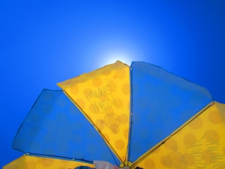 Beach umbrella with vibrant fabric patterns fluttering under a sunny sky.