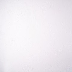 A plain white textured wall with a subtle stucco pattern. The wall shows swirled designs that create a slightly bumpy and irregular surface.
