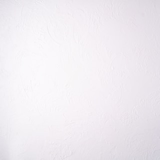 A plain white textured wall with a subtle stucco pattern. The wall shows swirled designs that create a slightly bumpy and irregular surface.