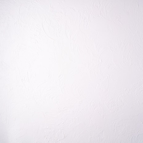 A plain white textured wall with a subtle stucco pattern. The wall shows swirled designs that create a slightly bumpy and irregular surface.