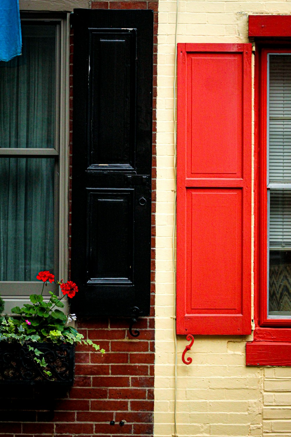 a brick building with a red window and a black shutter