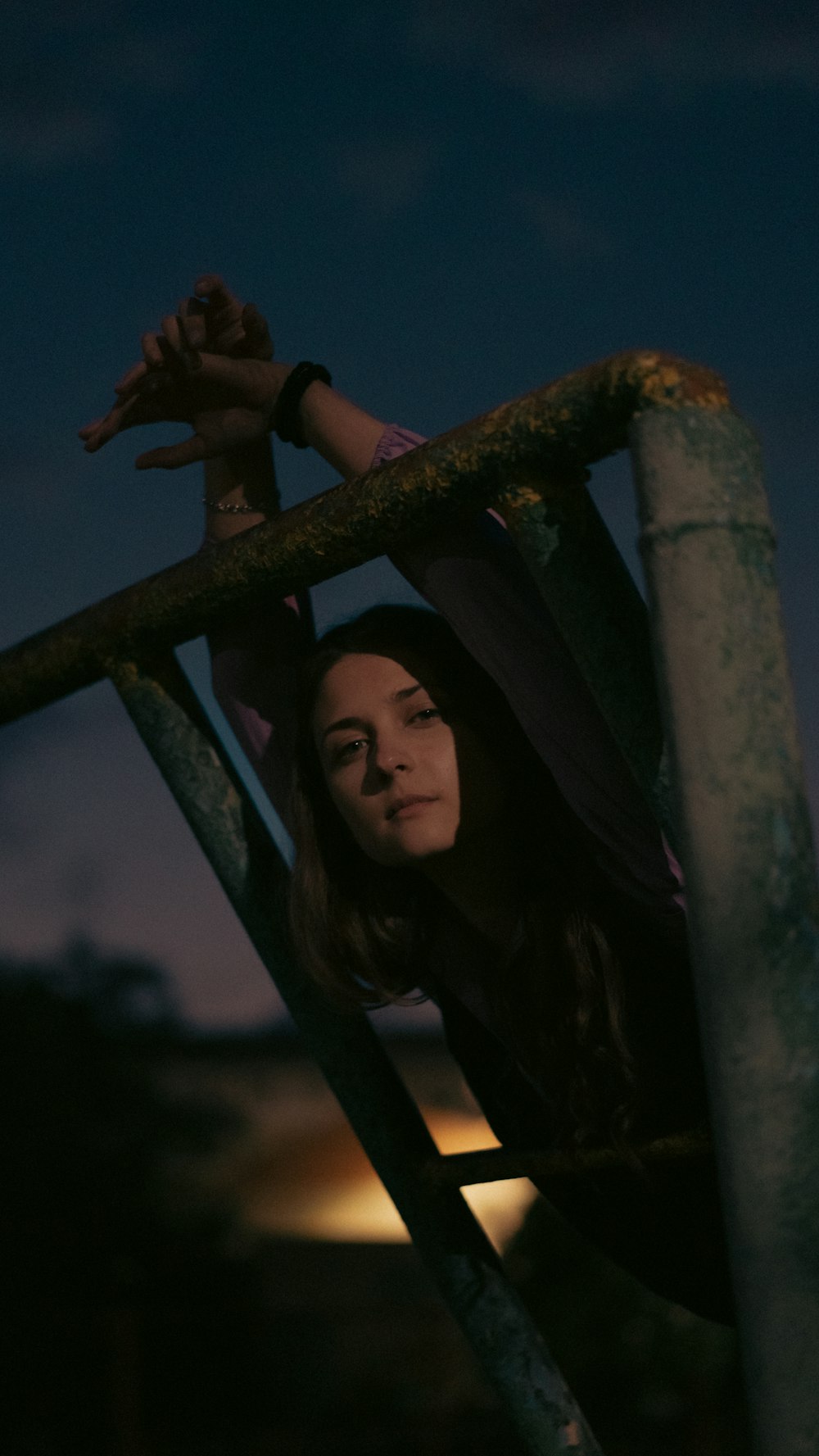 a woman leaning on a metal rail at night