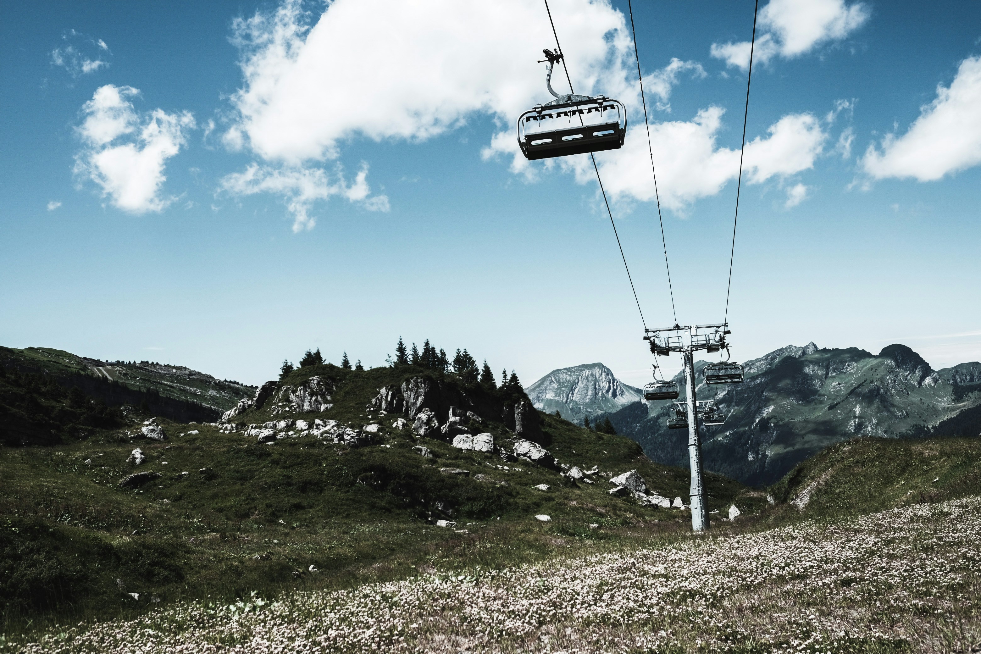 a ski lift going up a hill with mountains in the background, 