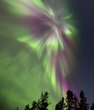 a green and purple aurora bore in the night sky
