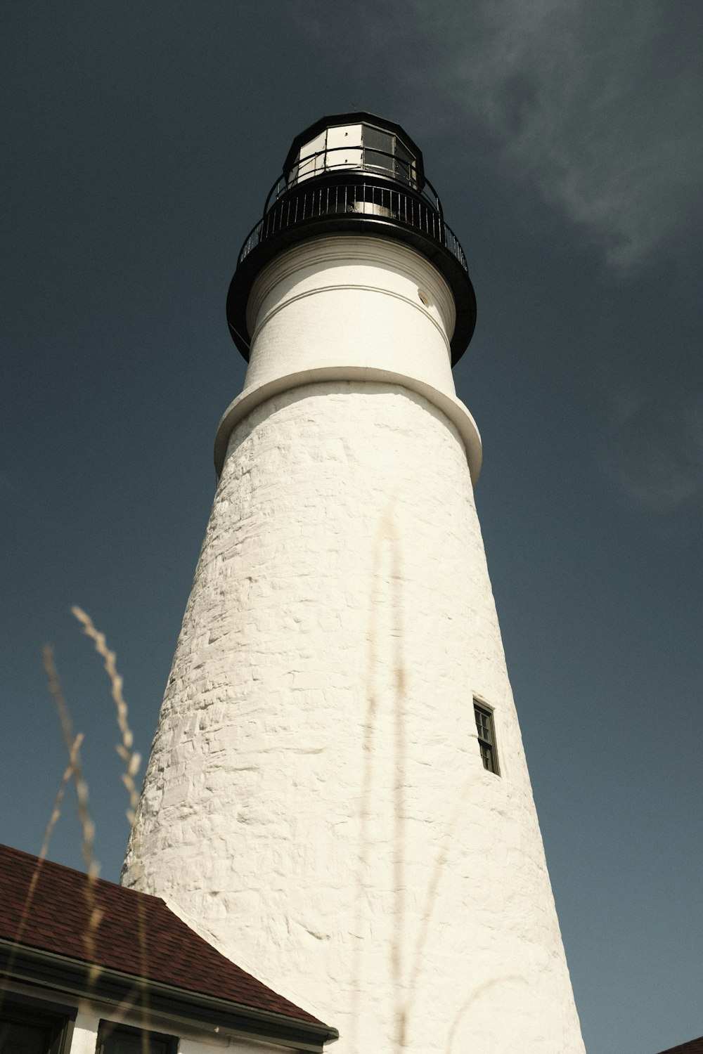 a white lighthouse with a brown roof on a sunny day
