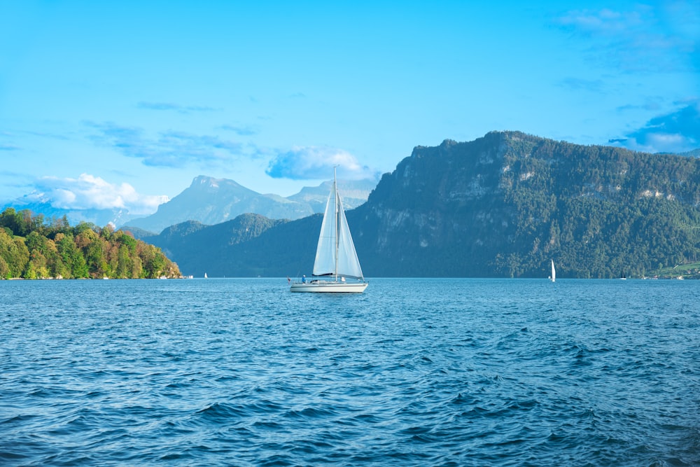 a sailboat on a lake with mountains in the background