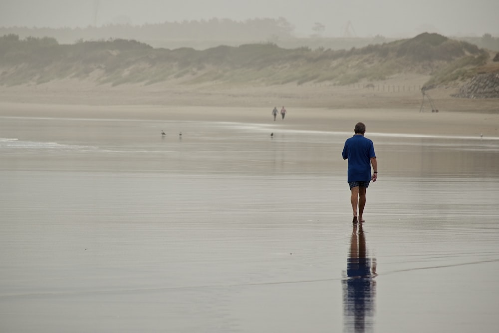 a man walking on the beach with his surfboard