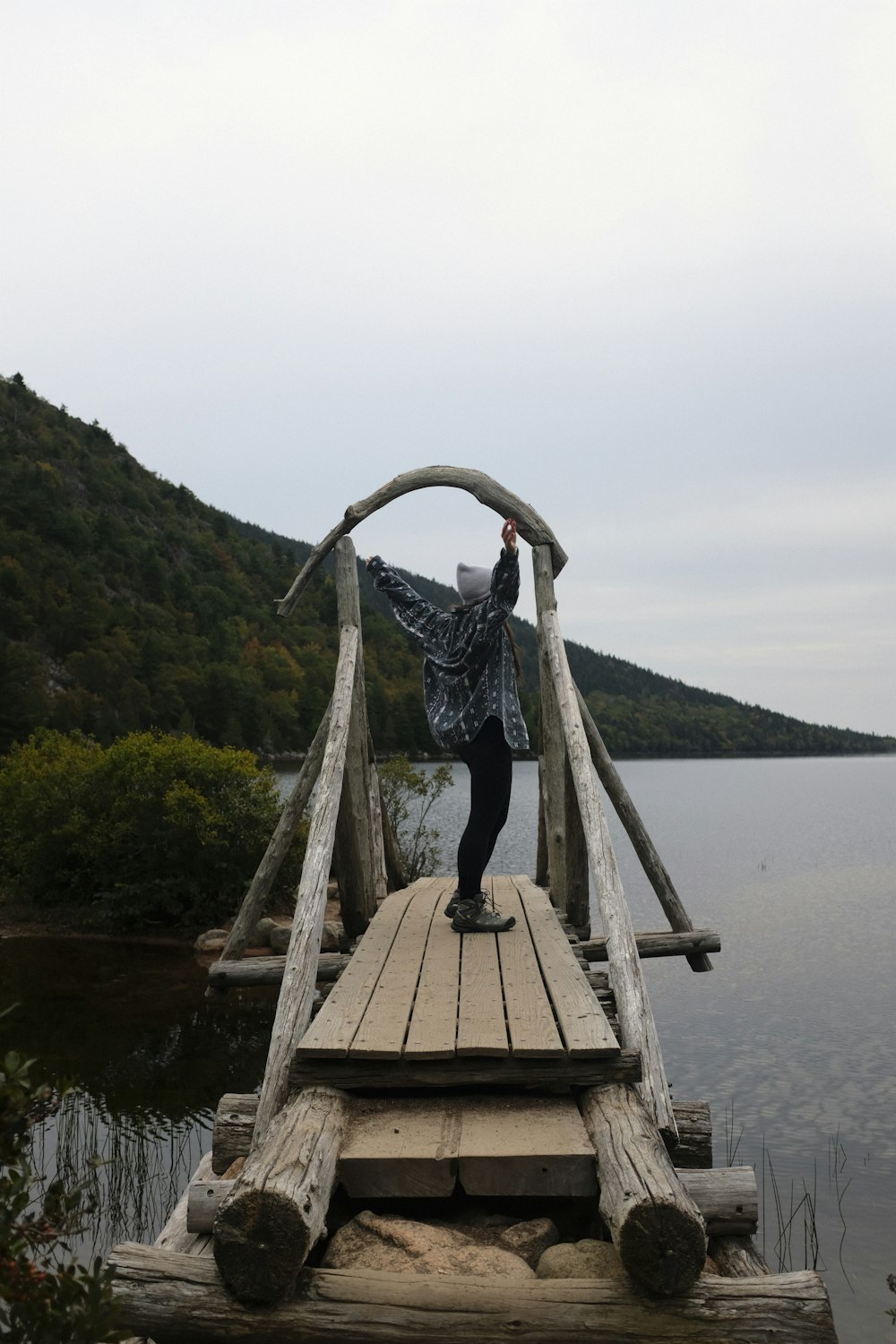 a person standing on a wooden bridge over a body of water
