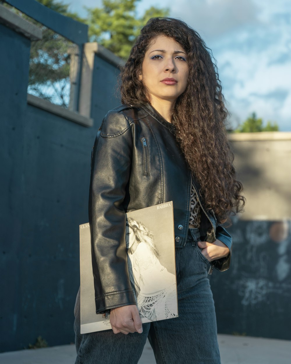 a woman in a black leather jacket holding shopping bags