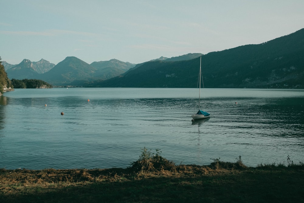 a boat floating on top of a lake surrounded by mountains