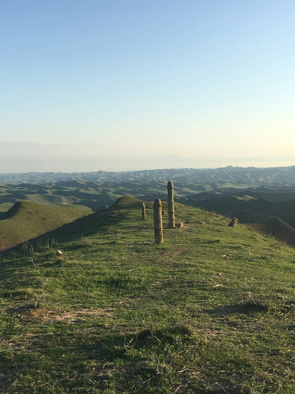 a grassy hill with a wooden post in the middle of it