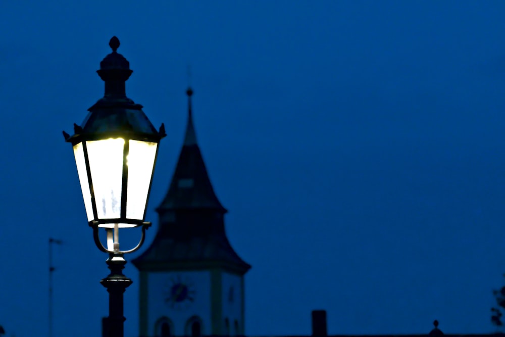 a street light with a clock tower in the background