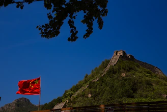 A vibrant photo of the Great Wall of China winding over green hills under a clear blue sky.
