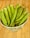 A ceramic bowl filled with fresh green okra pods is placed on a wooden surface. The okra pods appear fresh with a slightly glossy texture.