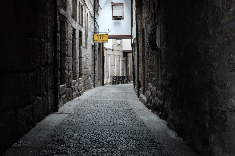 a narrow alley way with a yellow street sign