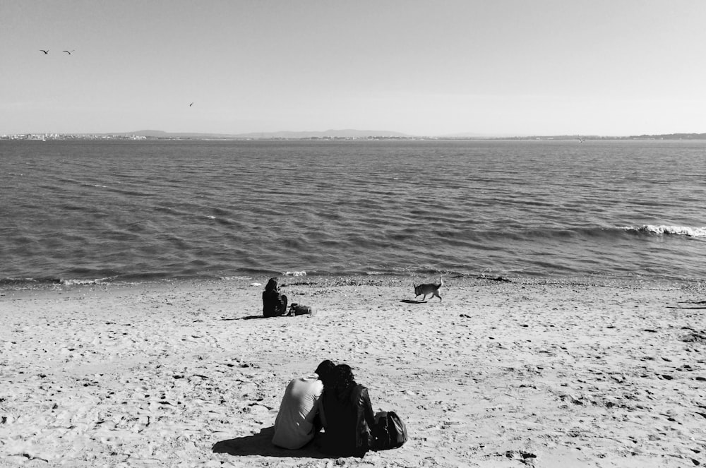 a couple of people sitting on top of a sandy beach