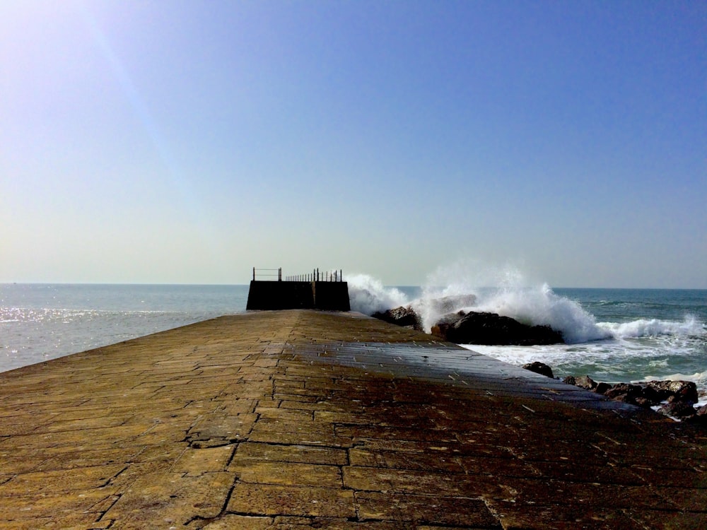 waves crashing against a break wall on a sunny day