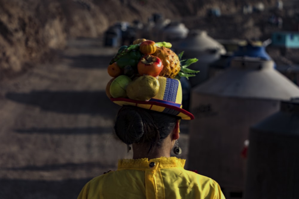 a woman wearing a hat with fruit on top of her head