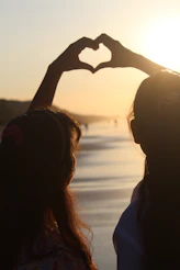 two women making a heart shape with their hands