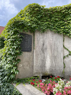 Close-up of a black and white memorial plaque with a QR code on a gravestone surrounded by soft morning light