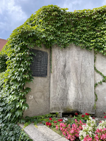 Close-up of a black and white memorial plaque with a QR code on a gravestone surrounded by soft morning light