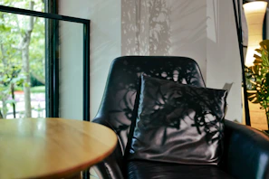 A serene image of a softly lit corner featuring a sleek black leather chair with golden accents.