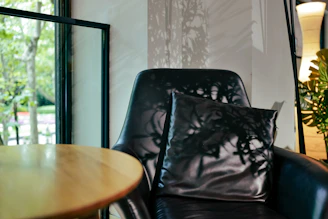 A serene image of a softly lit corner featuring a sleek black leather chair with golden accents.