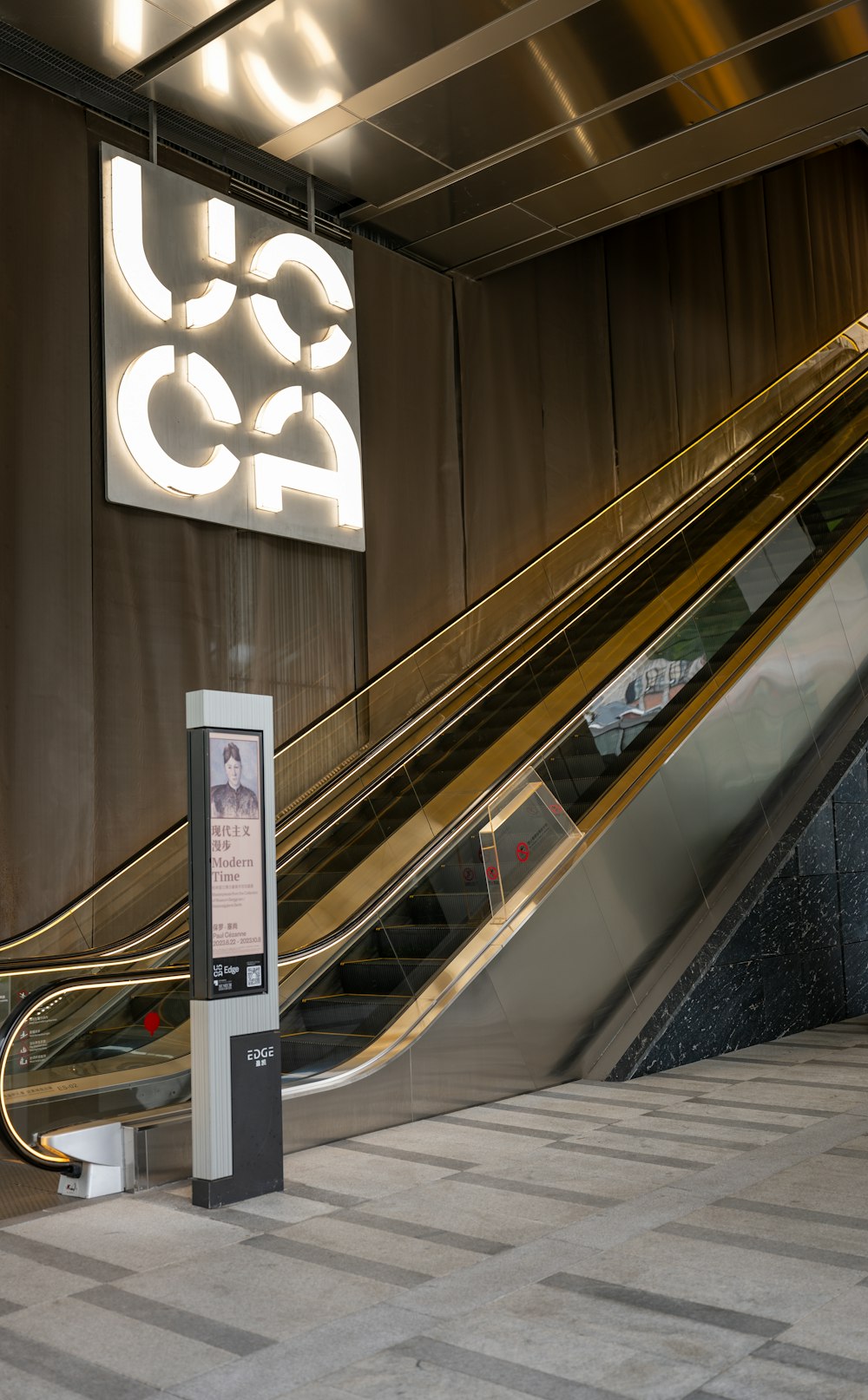 an escalator in a subway station with a sign on the wall