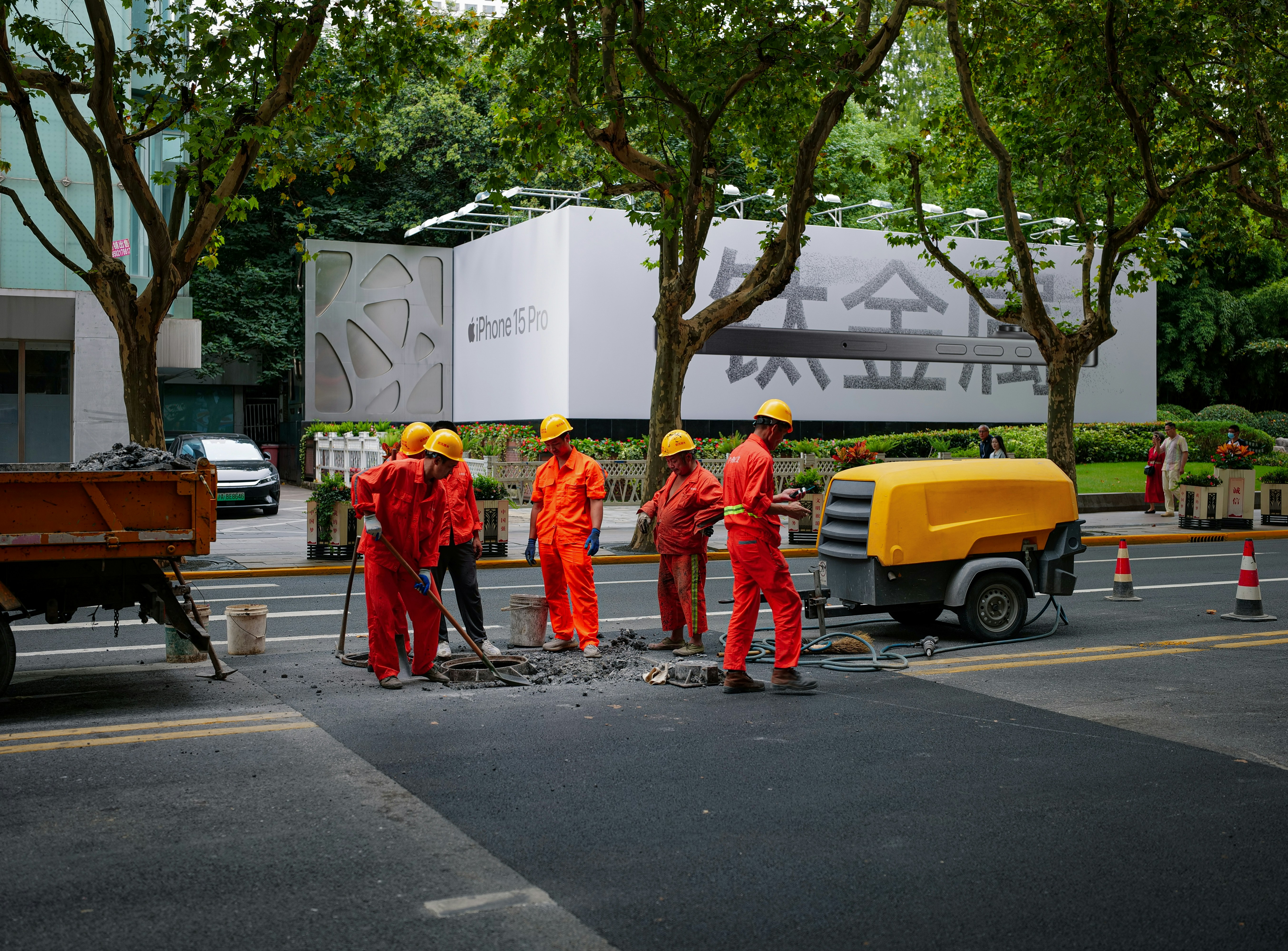A group of happy tribal villagers, including children, walking on a newly built bridge over a river, smiling and waving.
