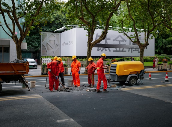 A group of construction workers discussing job opportunities on a smartphone outdoors.