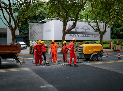 A team of construction workers repairing a pothole on a sunny day.