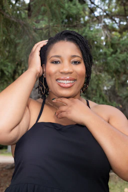 A warm photo of Bia smiling outdoors, surrounded by greenery, embodying calm and balance.