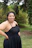 A confident woman posing outdoors wearing a flattering, curve-enhancing dress.