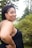 A smiling woman standing amidst lush green trees in the Amazon.
