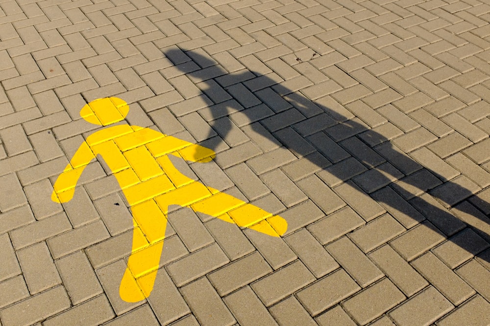 a yellow pedestrian crossing sign on a brick road
