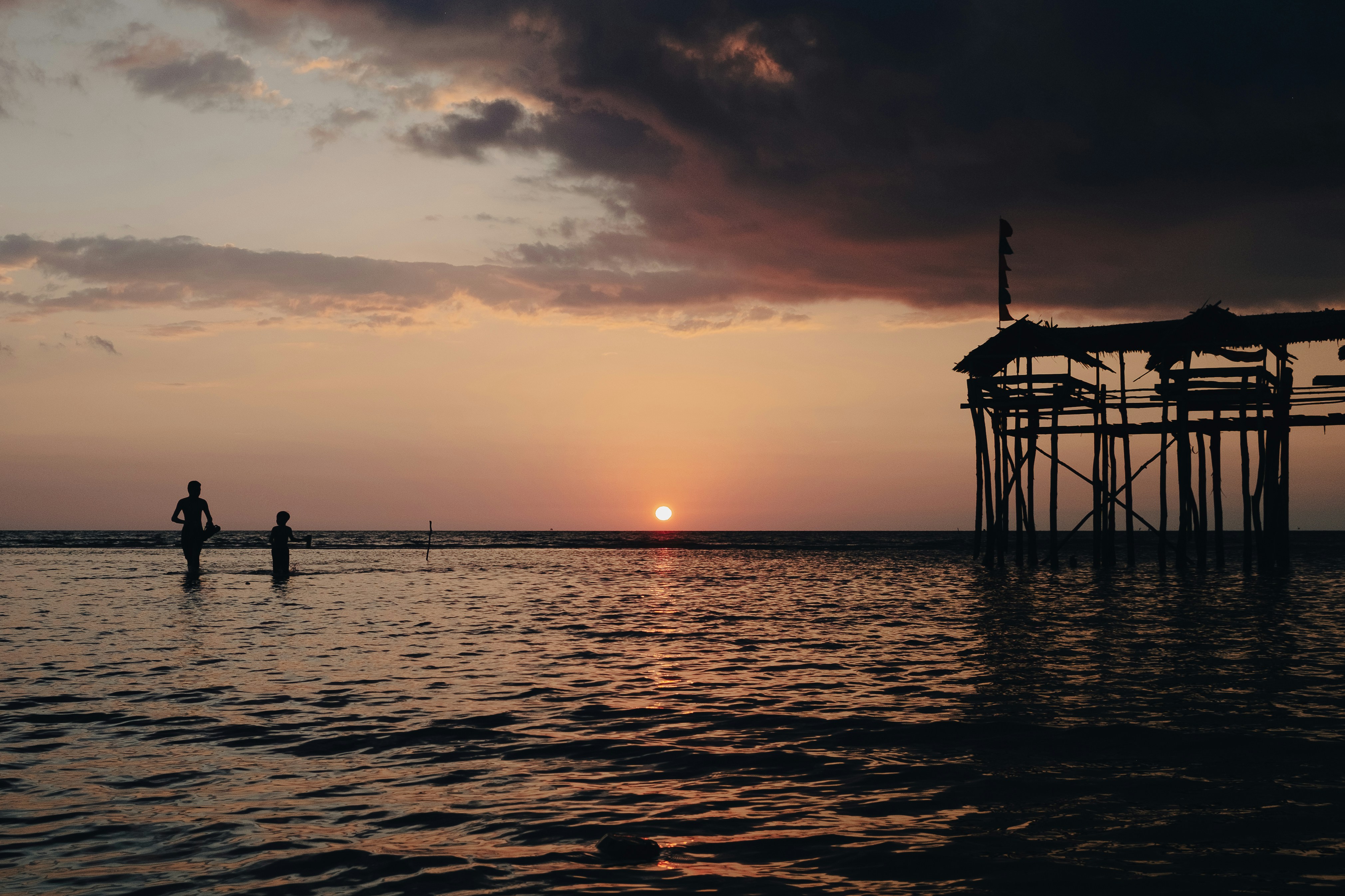 a couple of people in a body of water at sunset