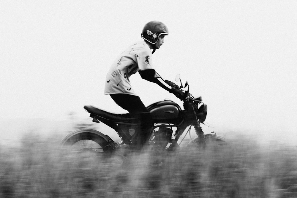 a black and white photo of a person riding a motorcycle