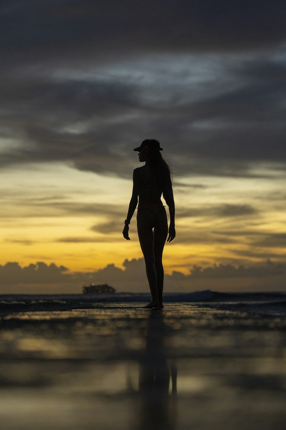 a woman walking on the beach at sunset