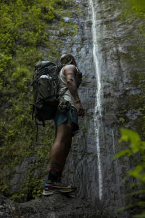 Adventurous hikers standing at the edge of Tumpak Sewu waterfall, surrounded by lush greenery.