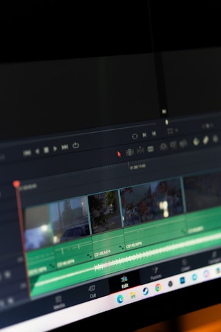 A computer screen displaying video editing software with a timeline view. The timeline includes clips, audio tracks, and a toolbar with options for cutting and editing. The background is dark, emphasizing the software interface.