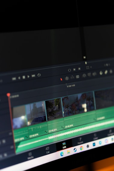 A computer screen displaying video editing software with a timeline view. The timeline includes clips, audio tracks, and a toolbar with options for cutting and editing. The background is dark, emphasizing the software interface.