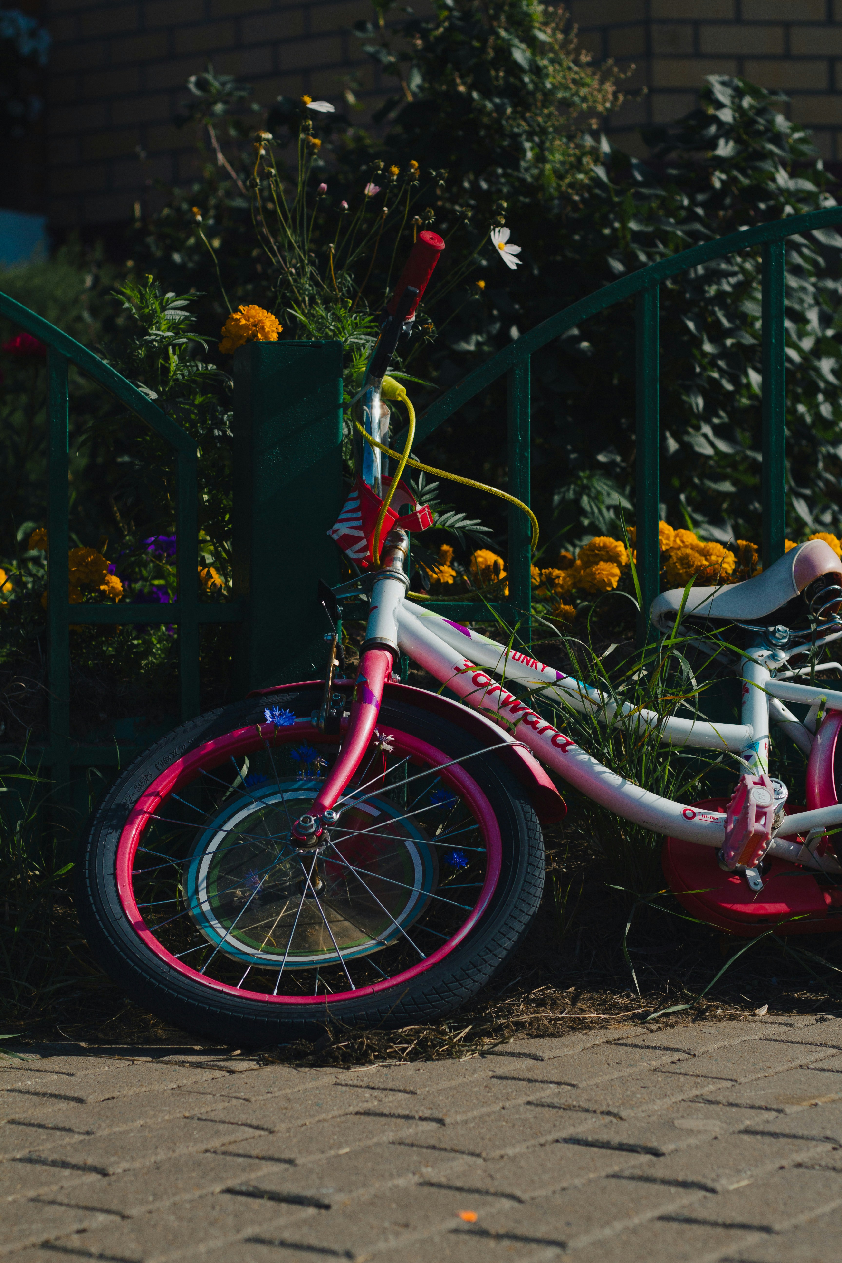 a pink bicycle parked next to a green fence