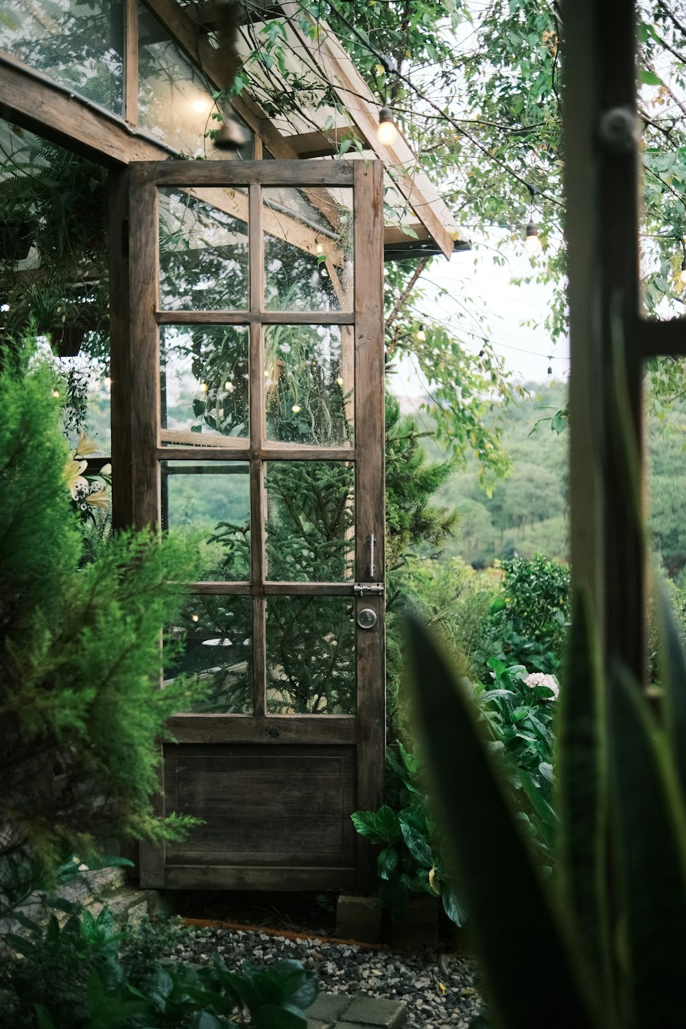 Una puerta de madera está abierta en un jardín